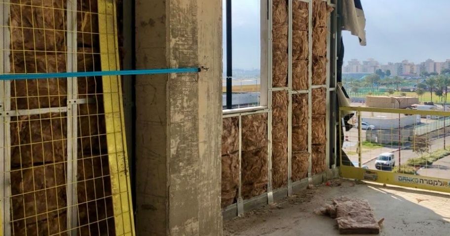 קיר מסך בשלב ביצוע עם מילוי בידוד תרמי באתר בנייה ירוקה